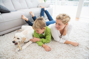 Family with dog laying on a rug. The Furniture Shack serving Portland OR and Vancouver WA offers furniture care service to protect your furniture.